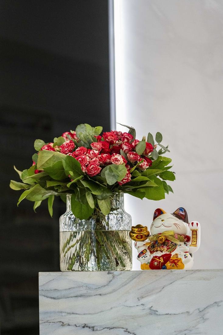 Blumenstrauss und Glückskatze auf dem Marmortresen
