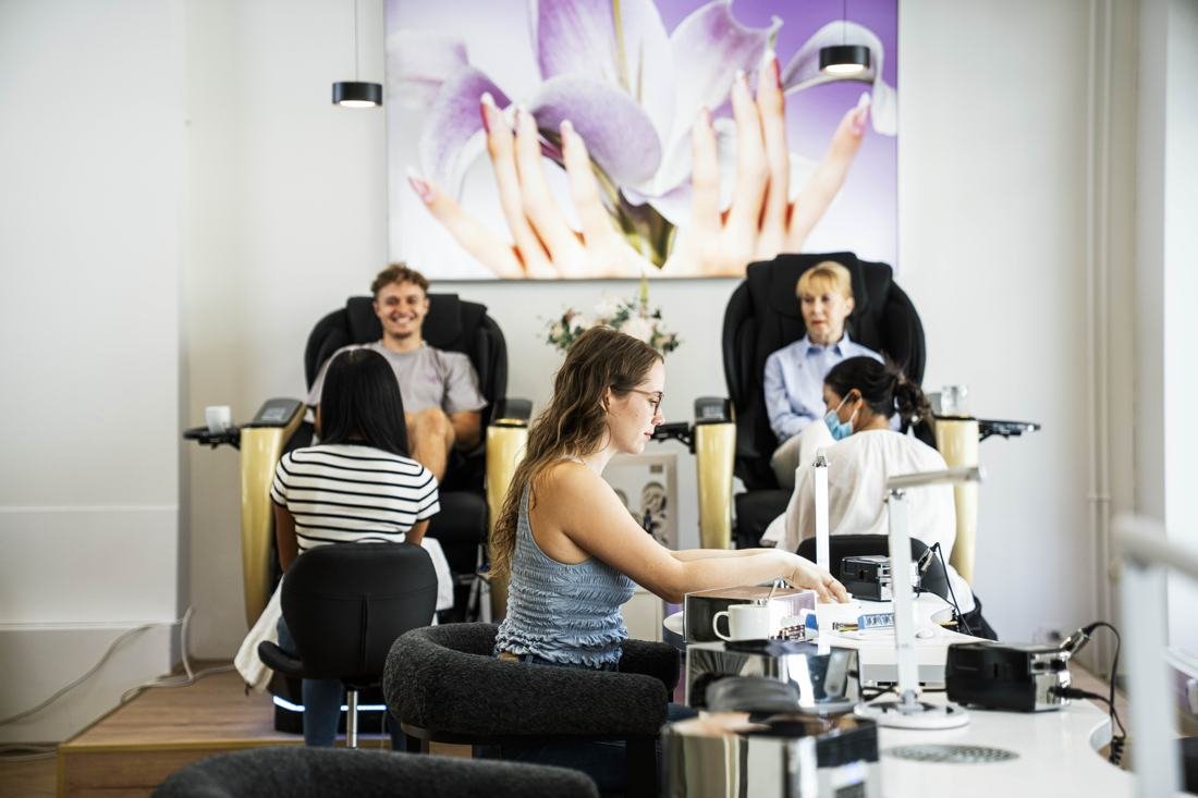 Pediküre-Throne vor dem Lilienbild mit Nageldesignerinnen bei der Arbeit