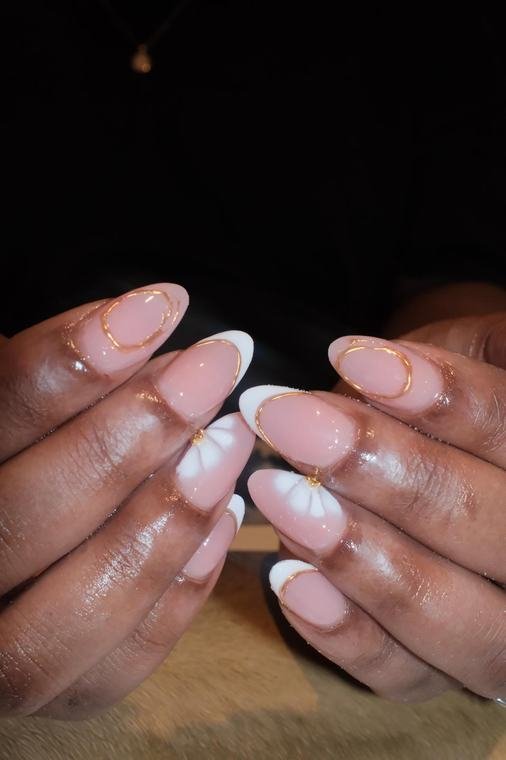 Nude Nägel mit goldenen Konturlinien und weisser Blüte